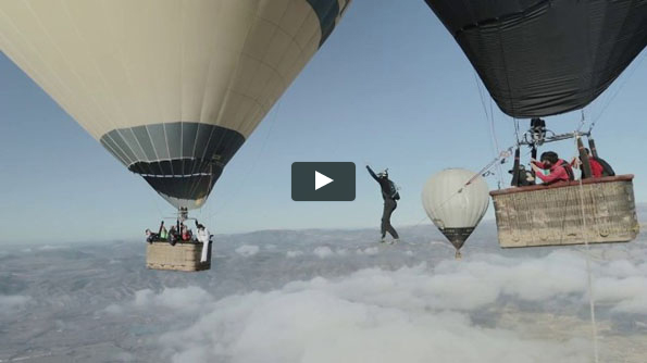 Guys Walk Tightrope Between Hot Air Balloons