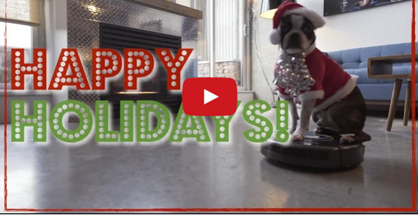 A Boston Terrier Dressed As Santa Claus Riding A Roomba