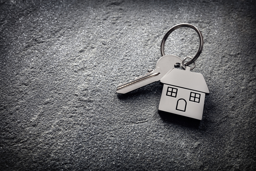 House key on a house shaped keychain on stone concept for real e