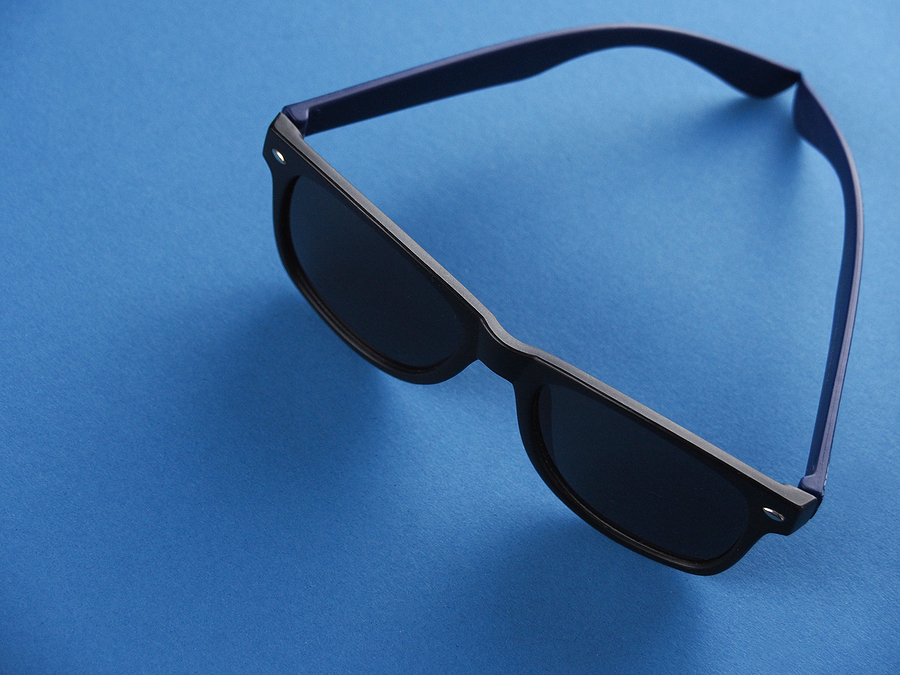 Sunglasses Layoners Black Square-shaped Sunglas With Blue Earhooks Against A Blue Ba