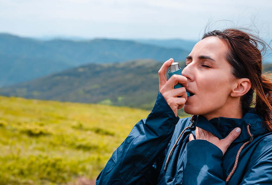 Here’s How Humidifiers Can Help Reduce Asthma Symptoms Woman Hiker Taking Asthma Pump Inhalation. Woman Asthma Puffing.