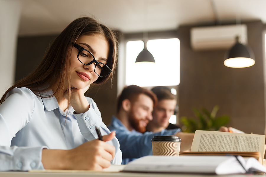 Smart Girl Student Studying At Library, Writing Essay And Drinki