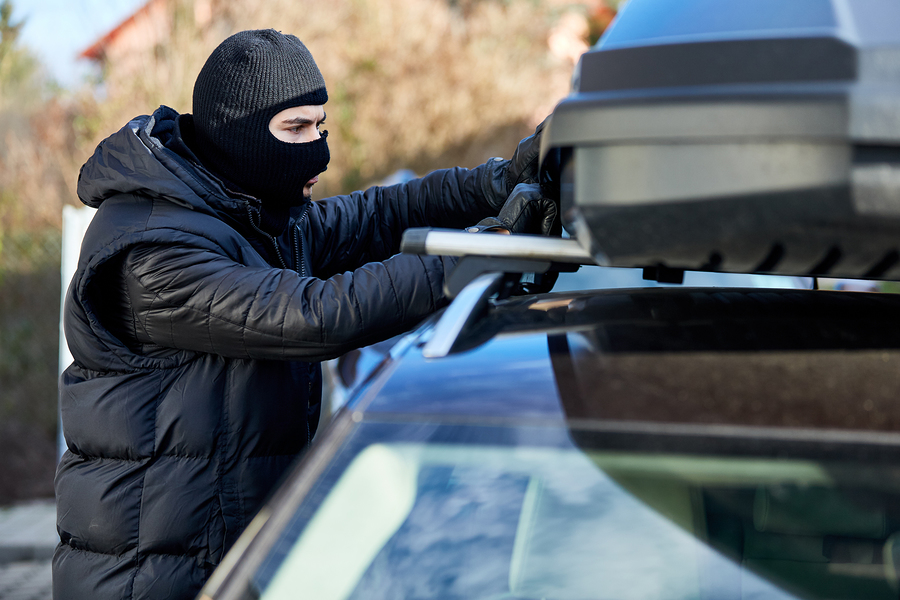 Thief opens roof box or roof rack on a car for theft