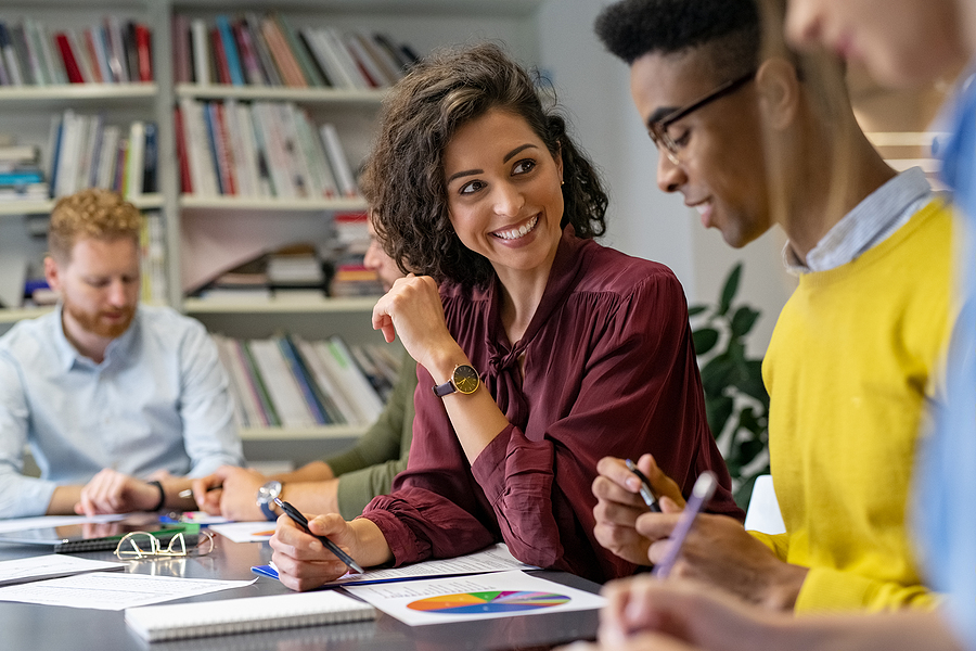 Multiethnic business people discussing together their strategy. Happy businesswoman showing marketing strategy african businessman. Creative business team talking and smiling during brainstorming.