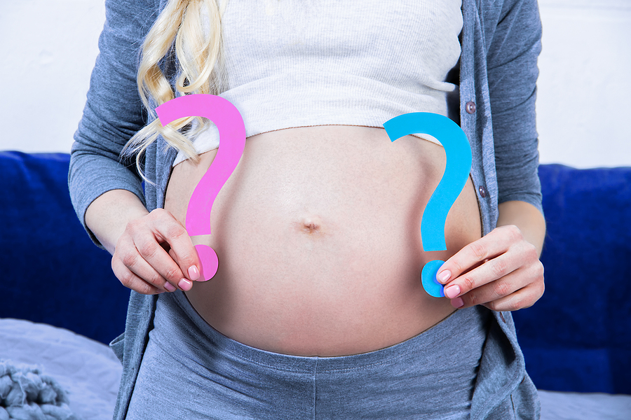 How to include a gender reveal at your baby shower Young Woman Is Holding Pink And Blue Paper Question Signs Near T