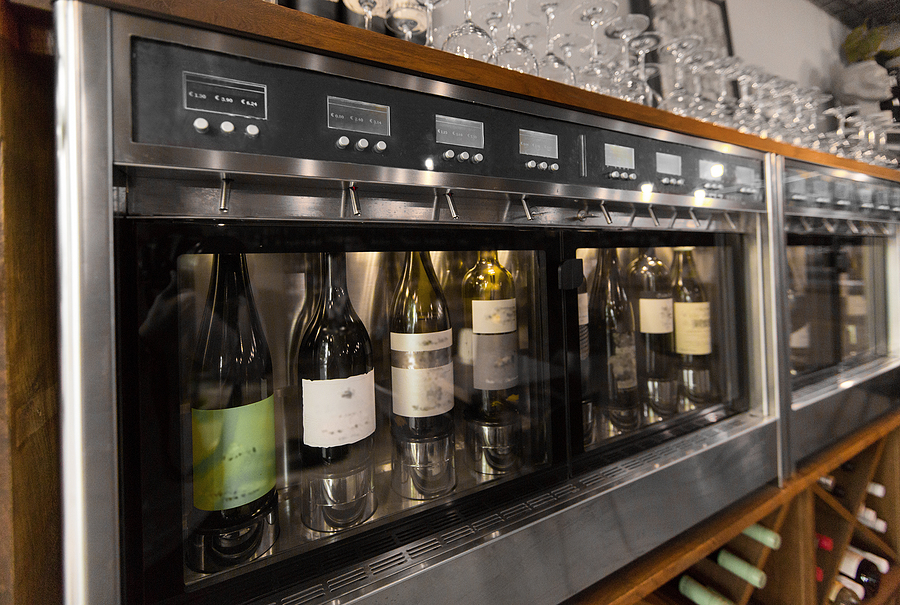 How to Choose the Right Wine Dispenser for Your Restaurant alcohol, technology and storage concept – close up of wine bottl