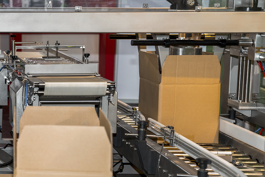 cardboard box of product packaging is moving on conveyor belt of automatic packing machine in the manufacturing factory ready for distribution to market. logistic manufacturing and industrial concept.