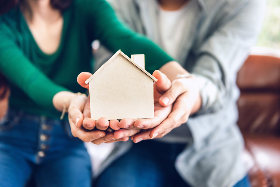 What Is The Easiest Loan For Canadians To Get Approved For? Couple Hands Holding Housing Model for Future Real Estate Saving, People Hand Joint to Protection Home Property Togetherness. House Insurance and Residential Loan Investment Concept.