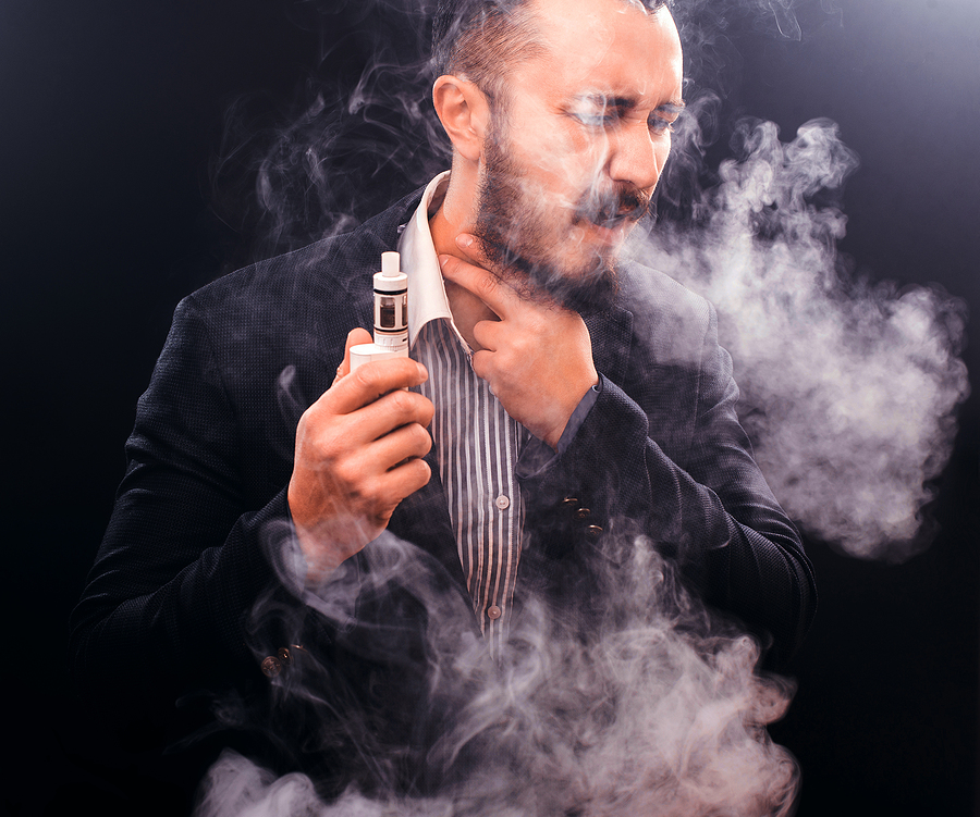 Man coughing a lot from vaping , on black background