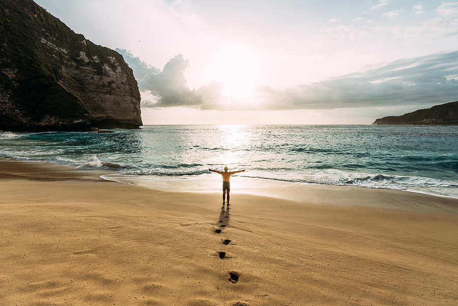 3 Ways To Balance Full-Time Work And Travel Lonely Man Stands On The Beach Looks Towards The Sun Light. A Ma