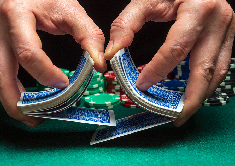 Casino Dealers' Job: What To Know To Become A Professional Close-up hands of a person-dealer or croupier shuffling poker cards in a poker club on the background of a table, chips. Poker game or gaming business concept