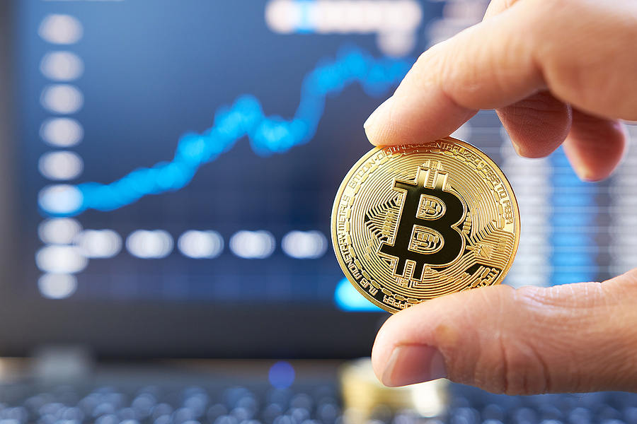 Bitcoin Prime Business Assistance App bitcoin Male hand showing gold bitcoin. laptop keyboard with basic candlestick green red graph price in background. Worldwide cryptocurrency and digital payment concepts. Bitcoin price rises