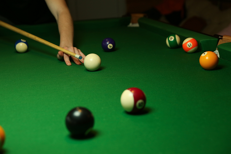 Play, win, and earn 8 ball pool real money by practicing game online pool tables pool balls and billiard cue on green billiard table. the hand of a billiard player holds a cue on a pool table. billiard player strikes a white ball