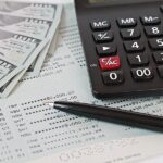Business, finance, saving money, banking, loans, investment, taxes money planning or accounting concept : American dollars cash money, calculator and pen on saving account book or financial statement