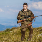 Qualities That You Need to Look For in a Hunting Rifle Hunter with hunting gun and hunting form to hunt. Hunter is aiming. Shooter sighting in the target. The man is on the hunt. Hunt hunting rifle. Hunter man. Hunting period. Male with a gun