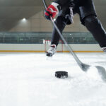 Male hockey player in sports uniform, gloves and skates moving d