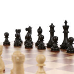 What Makes Portable Wooden Chess Sets A Great Choice? Set Of Black Chess Pieces On Wooden Board Against White Backgrou