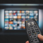 Exploring the Future of Television through Streaming Platforms VOD service on television. Man watching TV, streaming service, video on demand, remote control in hand. subscription services