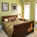 Four Reasons To Use A Low Profile Ceiling Fan Sleigh bed in a green bedroom with a ceiling fan and wall art. Vertical shot.