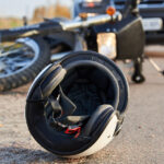 7 Haunting Motorcycle Accident Facts Photo of car, helmet and motorcycle on road, the concept of road accidents.