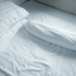 Close Up White Pillow And Bolster On White Bed In Home