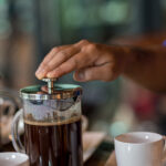 Hand preparing coffee in French Press Coffee Maker. Morning concept. coffee siphon. Spent coffee break at the organic cafe and prepare Chocolate or tea in French press.