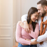 7 Best Ways to Create a Strong, Healthy, and Intimate Relationship Love And Affection. Young Couple In Love Hugging Standing Near Window At Home, Cuddling And Enjoying Time Together. Romantic Love And Relationship. Panorama, Free Space For Text