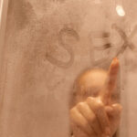 Why Condoms Are Vital in Every Sexual Encounter Portrait of beautiful woman taking a shower and writing word sex on the sweat and blurred glass, attractive female doing morning hygiene procedures, body care.