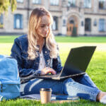 From Understanding the Prompt to Proper Formatting: The A to Z of Academic Essay Writing Attractive smiling student dressed casually studying outdoors on campus lawn at the university. Young woman is reading book, sitting with laptop on green grass in college park. Education concept.