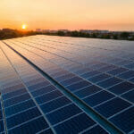 Types of energy-efficient roofs Blue photovoltaic solar panels mounted on building roof for producing clean ecological electricity at sunset. Production of renewable energy concept.