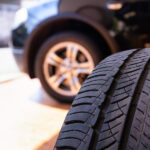 What Is the Difference between All-Weather Tires and Other Tires? Close up of old tire with car wheel background. Tire workshop and change old wheel on the car. Used car tires stacked in piles at tire fitting service repair shop