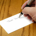 The Art of Personalised Thank You Cards: Tips for Impactful Messages Person writing thank you note with pen on card