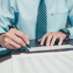 Understanding the Benefits of PSP Licenses for Payment Service Providers Business Man Hand Writing And Signing White Blank Bank Check Boo