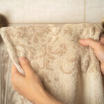 Where to Buy High-Quality Hand Towels? Female Hands Hang A Fresh Clean Towel On A Towel Holder Made In