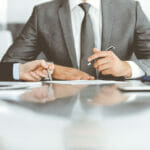 Unknown business people working together at meeting in modern office, close-up. Businessman and woman with colleagues or lawyers discussing contract at negotiation