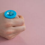 Is anal sex the next thing you should introduce to the bedroom? A Woman Is Holding A Blue Anal Plug With A Crystal On A Pink Bac