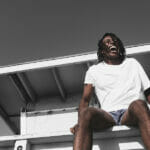 Seven Ways to Elevate a Basic Tee African American man in white tee at the beach
