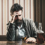 Understanding The Merits Of Residential Detox Programs In The United States Alcoholism. Addiction crisis. Alcohol addiction and people concept male alcoholic drinking cognac at night. Depressed man in bar with a bottle of alcohol. Stop addiction. Man crisis concept.