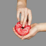 Mutual Masturbation: You Just Have to Try It. Here's Why. Female Hands And A Donut On A Grey Background As A Symbol Of Mas