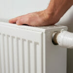 Hand adjusting temperature on heating radiator thermostat, Turning heat radiator knob to control heat in home