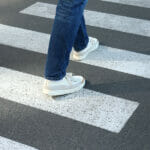 Trending Jean Styles for Men in 2022 Man In Jeans And Sneakers Walking On Crosswalk.