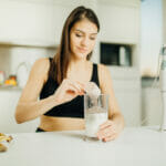 Woman With Immersion Blender Making Banana Chocolate Protein Pow