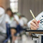 The Benefits of Pursuing Higher Education and the Role of Fake College and University Degrees in Motivation Exam at school with student's taking educational admission test in class, thinking hard, writing answer in university classroom, education and world literacy day concept