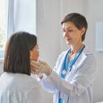 Friendly Middle-aged Woman Doctor Wearing Gloves Checking Sore T