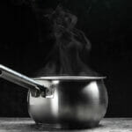 What to Consider Before Buying a Pot Set Steam Over Cooking Pot On Black Background, Hot Food. Bowl Of Ho