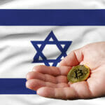 Golden Bitcoin Coin In Man’s Hand, Israel Flag In The Background