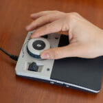A Woman Uses A Special Magnification Device For The Visually Imp