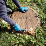 How often does septic tank pumping have to be done? A Working Plumber Opening Septic System Tank. Copy Space For Tex