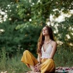 A Young Hippie Woman Meditates In Nature In The Park, Sitting In