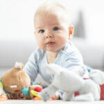 Four Signs Of Clogged Milk Ducts Cute baby boy playing with toys on mat at home Baby activity and play center for early infant development. Baby playing at home.